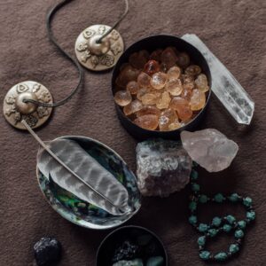 Flat lay of healing crystals, tingsha cymbals, and feathers for spiritual practices.